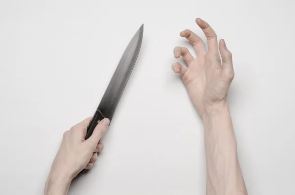 Mord och Halloween tema: en mans hand att nå för en kniv, en mänsklig hand håller en kniv isolerad på en grå bakgrund i studio från ovan — Stockfoto