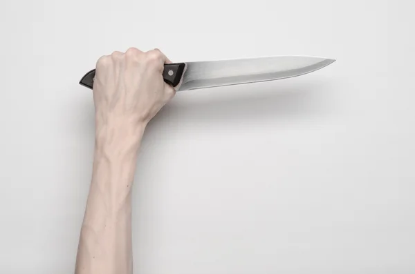 Тема убийства и Хэллоуина: рука мужчины тянется за ножом, человеческая рука держит нож изолированный на сером фоне в студии сверху — стоковое фото