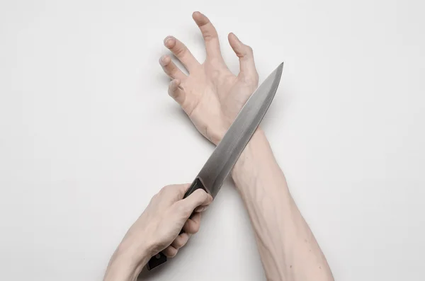 Motyw zabójstwa i Halloween: ręka mężczyzny sięgnąć nożem, ludzką ręką trzymając nóż na białym tle na szarym tle w studio z góry — Zdjęcie stockowe
