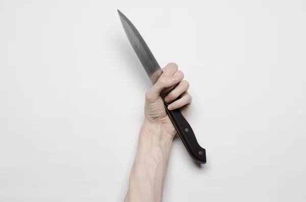 Murder and Halloween theme: A man's hand reaching for a knife, a human hand holding a knife isolated on a gray background in studio from above — Stock Photo, Image