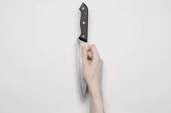 El asesinato y el tema de Halloween: La mano de un hombre que busca un cuchillo, una mano humana que sostiene un cuchillo aislado sobre un fondo gris en el estudio desde arriba — Foto de Stock