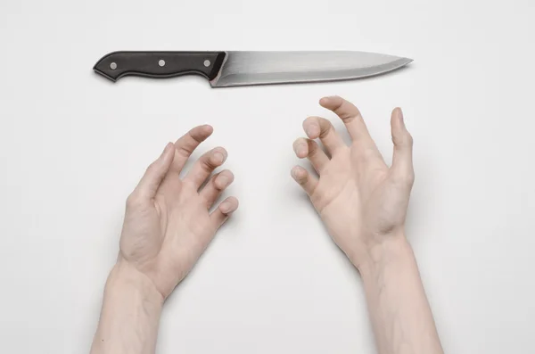 Murder and Halloween theme: A man's hand reaching for a knife, a human hand holding a knife isolated on a gray background in studio from above — Stock Photo, Image