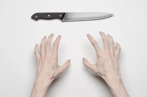 Murder and Halloween theme: A man's hand reaching for a knife, a human hand holding a knife isolated on a gray background in studio from above — Stock Photo, Image