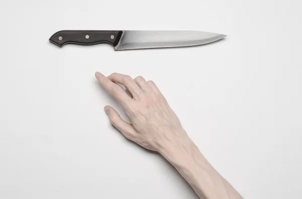 El asesinato y el tema de Halloween: La mano de un hombre que busca un cuchillo, una mano humana que sostiene un cuchillo aislado sobre un fondo gris en el estudio desde arriba — Foto de Stock