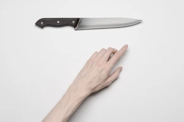 Murder and Halloween theme: A man's hand reaching for a knife, a human hand holding a knife isolated on a gray background in studio from above — Stock Photo, Image