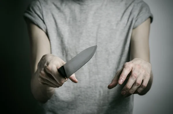 Thème Meurtre et Halloween : un homme tenant un couteau sur un fond gris — Photo