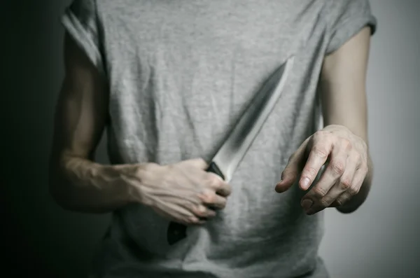 Murder and Halloween theme: a man holding a knife on a gray background — Stock Photo, Image