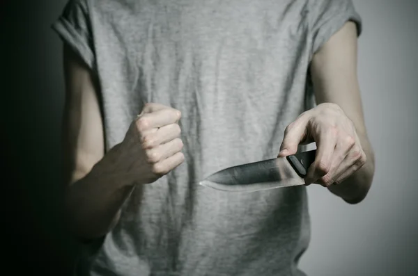 Murder and Halloween theme: a man holding a knife on a gray background — Stock Photo, Image