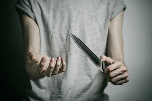 Тема убийства и Хэллоуина: человек, держащий нож на сером фоне — стоковое фото