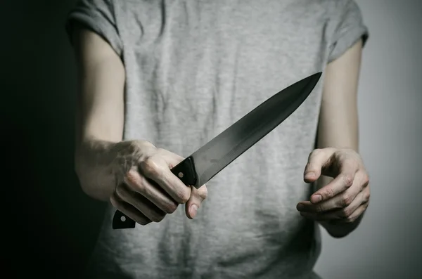 Murder and Halloween theme: a man holding a knife on a gray background — Stock Photo, Image