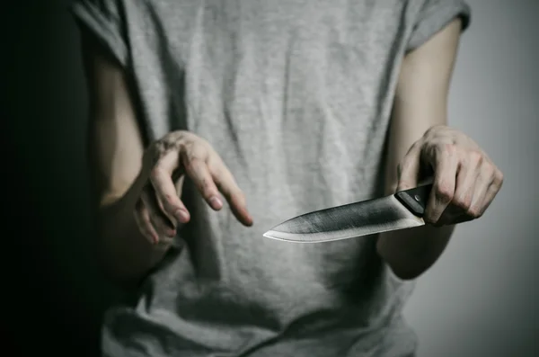 Mord und Halloween-Thema: Ein Mann mit einem Messer vor grauem Hintergrund — Stockfoto