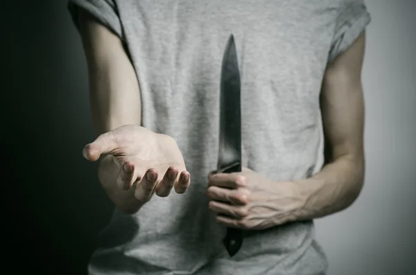 谋杀和万圣节的主题: 一个人抱着一把刀在灰色的背景上 — 图库照片