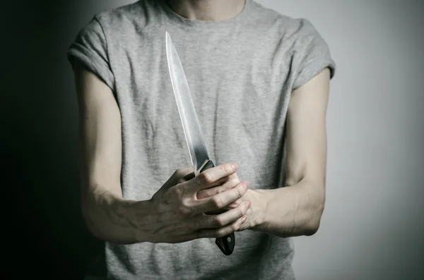 Murder and Halloween theme: a man holding a knife on a gray background — Stock Photo, Image