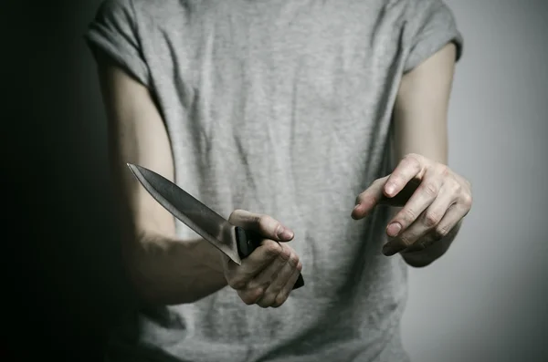 Mord och Halloween tema: en man som håller en kniv på en grå bakgrund — Stockfoto