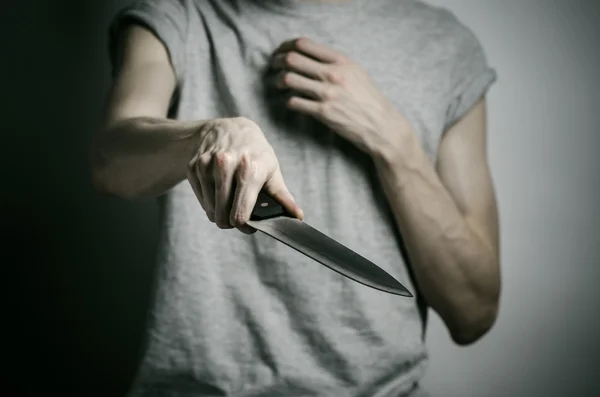 Motyw zabójstwa i Halloween: człowiek trzyma nóż na szarym tle — Zdjęcie stockowe