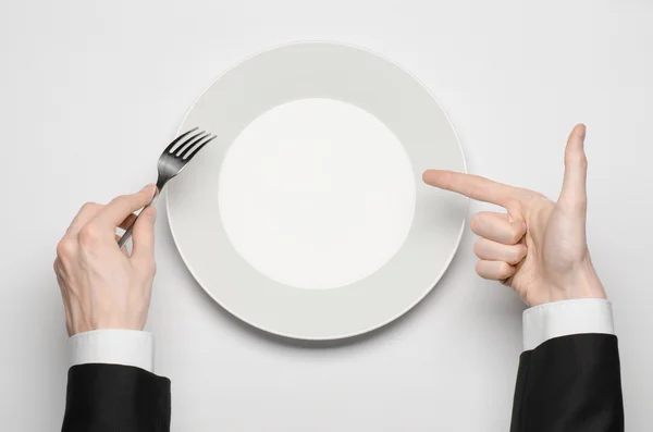 Almoço de negócios e tema de comida saudável: mão de homem em um terno preto segurando um prato branco vazio e mostra gesto de dedo em um fundo branco isolado na vista superior do estúdio — Fotografia de Stock
