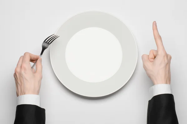 Бізнес-ланч і тема здорової їжі: рука людини в чорному костюмі тримає білу порожню тарілку і показує жест пальця на ізольованому білому тлі в студії вид зверху — стокове фото