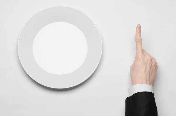 비즈니스 런치 및 건강 한 음식 테마: 흰색 빈 접시를 들고 검은 양복에 손을 인간과 스튜디오 평면도에 고립 된 흰색 바탕에 손가락 제스처를 보여줍니다 — 스톡 사진