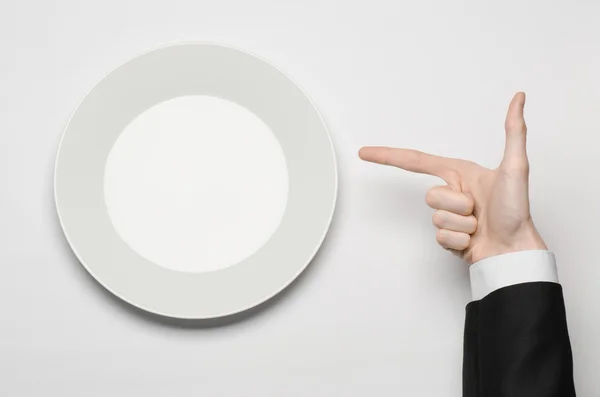İş öğle yemekleri ve sağlıklı gıda Tema: adam elinden tutan bir beyaz boş tabak siyah takım elbiseli ve parmak hareketi izole beyaz arka plan üzerinde studio üst görünümünde gösterir — Stok fotoğraf