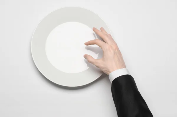 Almuerzo de negocios y comida saludable: la mano del hombre en un traje negro sosteniendo un plato blanco vacío y muestra el gesto del dedo sobre un fondo blanco aislado en la vista superior del estudio — Foto de Stock