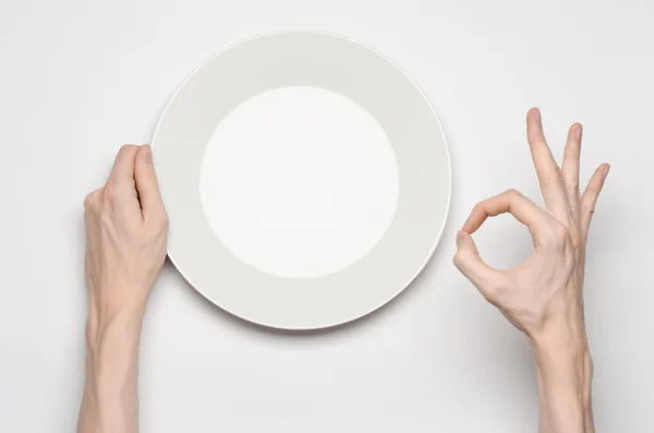 Tema Ristorante e Cibo: la mano umana mostra il gesto su un piatto bianco vuoto su uno sfondo bianco in studio isolato vista dall'alto — Foto Stock