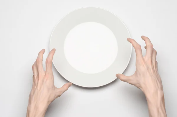 Тема ресторану та їжі: рука людини показує жест на порожній білій тарілці на білому тлі в студії ізольований вид зверху — стокове фото
