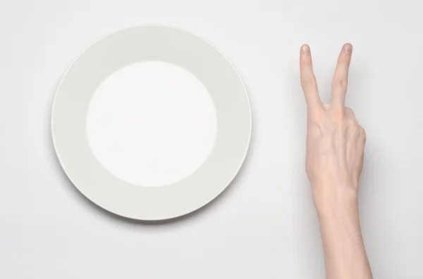 Restaurante e comida tema: o gesto de mão humana mostrar em uma placa branca vazia em um fundo branco em estúdio isolado vista superior — Fotografia de Stock