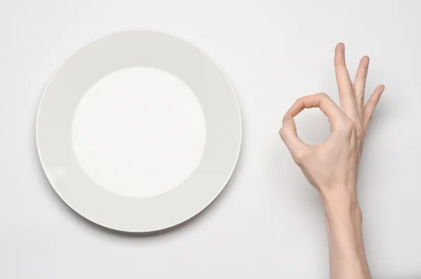 Restaurante e comida tema: o gesto de mão humana mostrar em uma placa branca vazia em um fundo branco em estúdio isolado vista superior — Fotografia de Stock