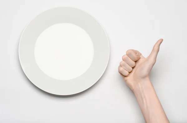 Тема ресторану та їжі: рука людини показує жест на порожній білій тарілці на білому тлі в студії ізольований вид зверху — стокове фото
