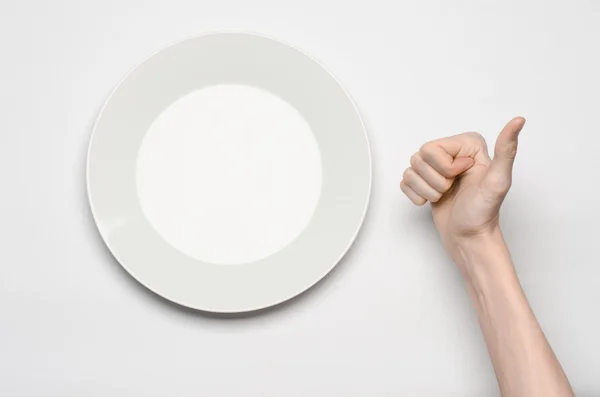 Ресторан и еда тема: жест человеческой руки шоу на пустой белой тарелке на белом фоне в студии изолированный вид сверху — стоковое фото