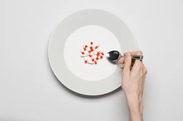 Φάρμακα και κακή διατροφή θέμα: ανθρώπινο χέρι κρατήστε πατημένο ένα πιάτο με χάπια που απομονώνονται σε λευκό φόντο κάτοψη — Φωτογραφία Αρχείου