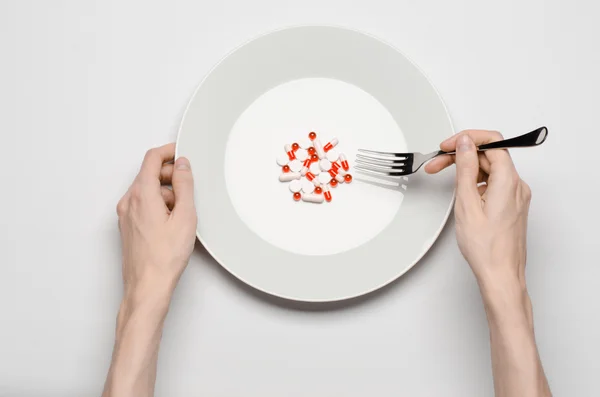 Medicamentos y nutrición inadecuada tema: mano humana sostiene un plato con pastillas aisladas en fondo blanco vista superior — Foto de Stock