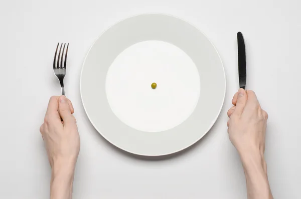 Tema de comida saudável: mãos segurando faca e garfo em um prato com ervilhas verdes em uma vista superior de mesa branca — Fotografia de Stock