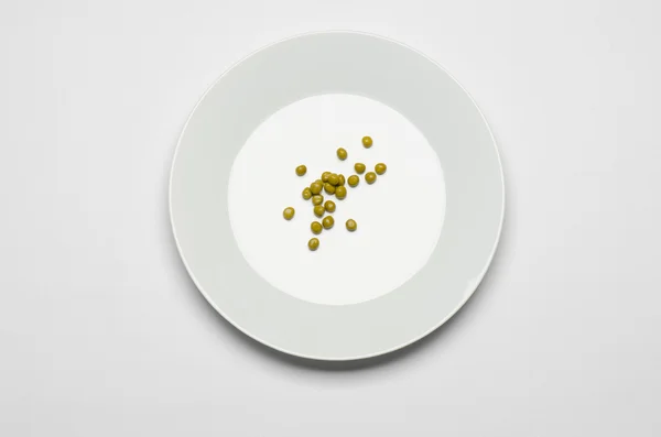 Тема здорового питания: зеленый горох, лежащий на белой тарелке на белом столе в студийном топе — стоковое фото