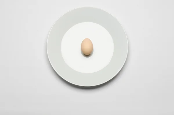 Um saudável dieta e pequeno-almoço tópico: ovo na casca encontra-se em uma placa branca sobre um fundo branco isolado em estúdio vista superior — Fotografia de Stock