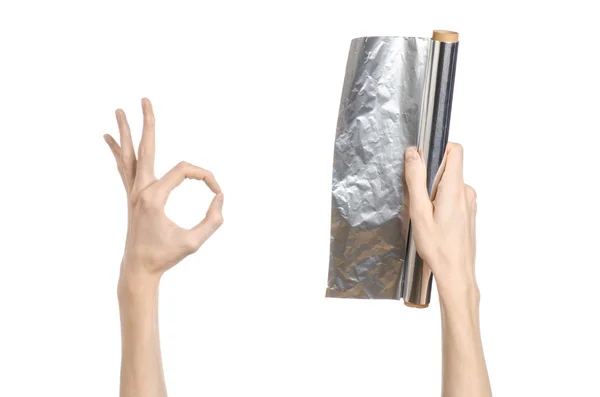 Тема кулинарии и каши: человеческая рука, держащая фольгу на белом фоне в студии — стоковое фото
