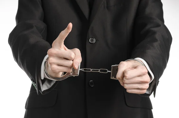 Corruption and bribery theme: businessman in a black suit with handcuffs on his hands on a white background in studio isolated Stock Photo