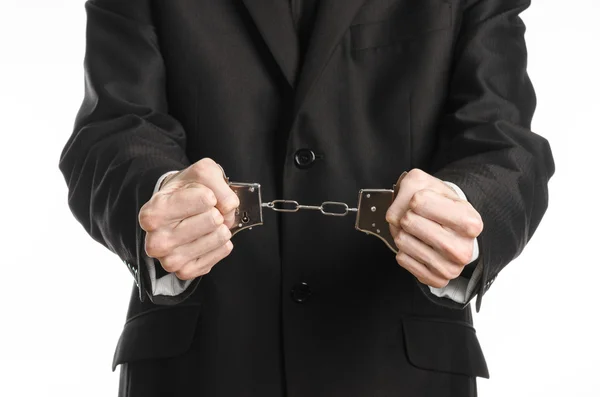 Corruption and bribery theme: businessman in a black suit with handcuffs on his hands on a white background in studio isolated Royalty Free Stock Images