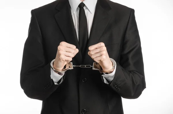 Corruption and bribery theme: businessman in a black suit with handcuffs on his hands on a white background in studio isolated Stock Image