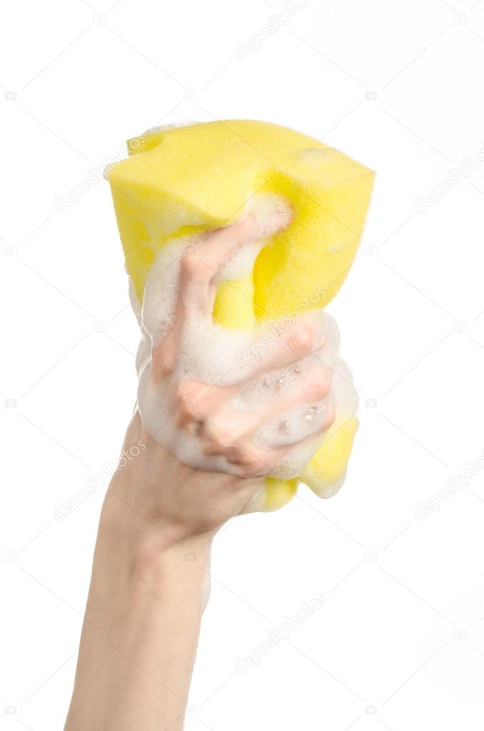 Cleaning the house and sanitation topic: Hand holding a yellow sponge wet with foam isolated on a white background in studio