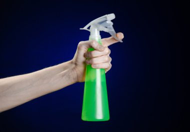 Temizlik ev ve temiz tema: koyu mavi bir arka plan üzerinde temizlik için bir yeşil püskürtülen ilaç şişe tutan adamın el