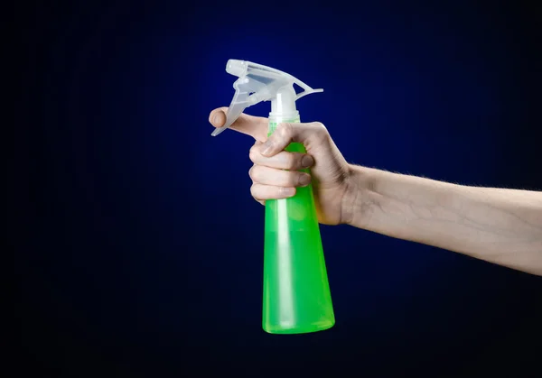 Úklid domu a čistší téma: ruka držící láhev zelený sprej pro čištění na tmavě modrém pozadí — Stock fotografie