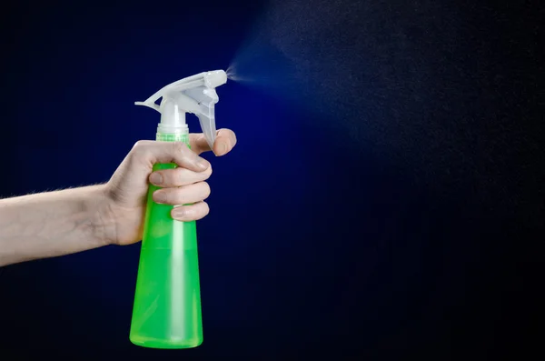 Nettoyage de la maison et thème plus propre : la main de l'homme tenant une bouteille de pulvérisation verte pour le nettoyage sur un fond bleu foncé — Photo