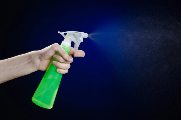 Membersihkan rumah dan tema yang lebih bersih: tangan manusia memegang botol semprotan hijau untuk membersihkan latar belakang biru tua — Stok Foto