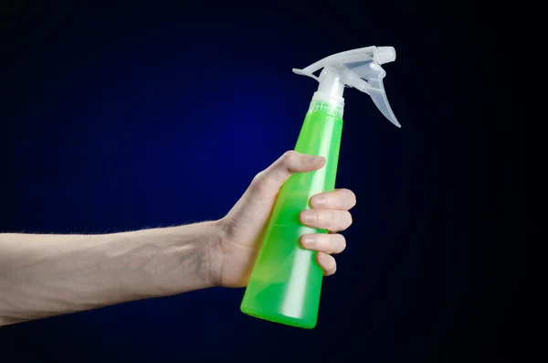 Limpieza de la casa y el tema más limpio: la mano del hombre sosteniendo una botella de spray verde para limpiar sobre un fondo azul oscuro — Foto de Stock