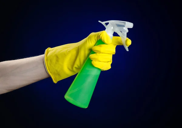 Pulizia della casa e tema più pulito: mano dell'uomo in un guanto giallo che tiene una bottiglia di spray verde per la pulizia su uno sfondo blu scuro — Foto Stock