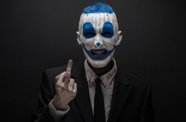 Terrible clown and Halloween theme: Crazy blue clown in black suit isolated on a dark background in the studio