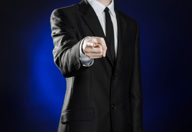Business and the presentation of the theme: man in a black suit showing hand gestures on a dark blue background in studio isolated