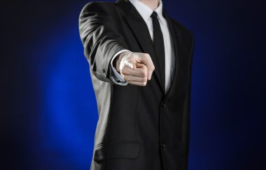 Business and the presentation of the theme: man in a black suit showing hand gestures on a dark blue background in studio isolated