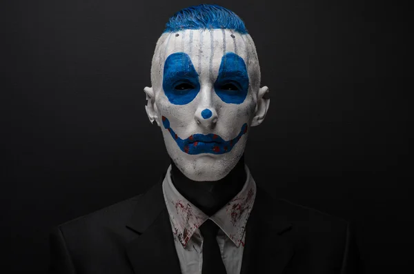 Schrecklicher Clown und Halloween-Thema: verrückter blauer Clown im schwarzen Anzug isoliert auf dunklem Hintergrund im Studio — Stockfoto